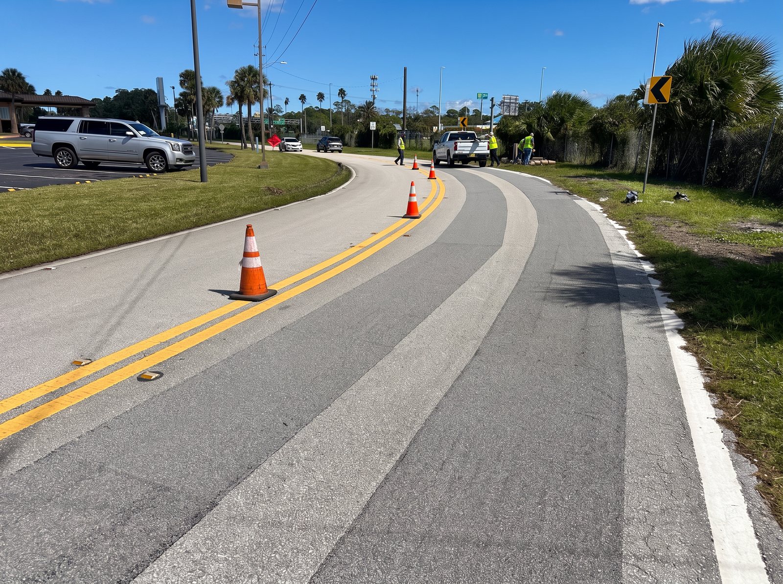 Crew and application truck installing Roadway Safety Strip high-friction lanes on a curved roadway, marked with traffic cones